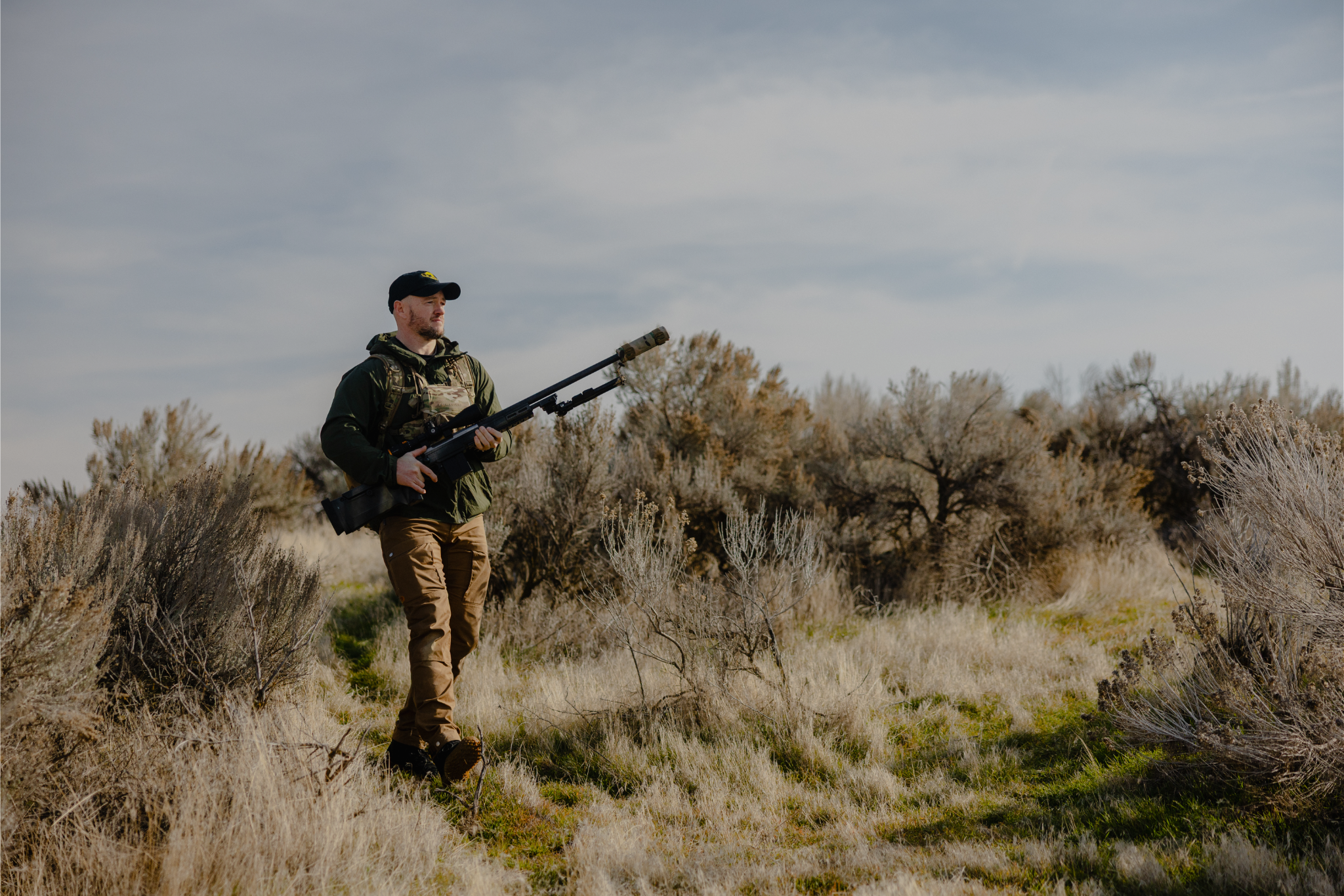 Shooter carrying a rifle in open country